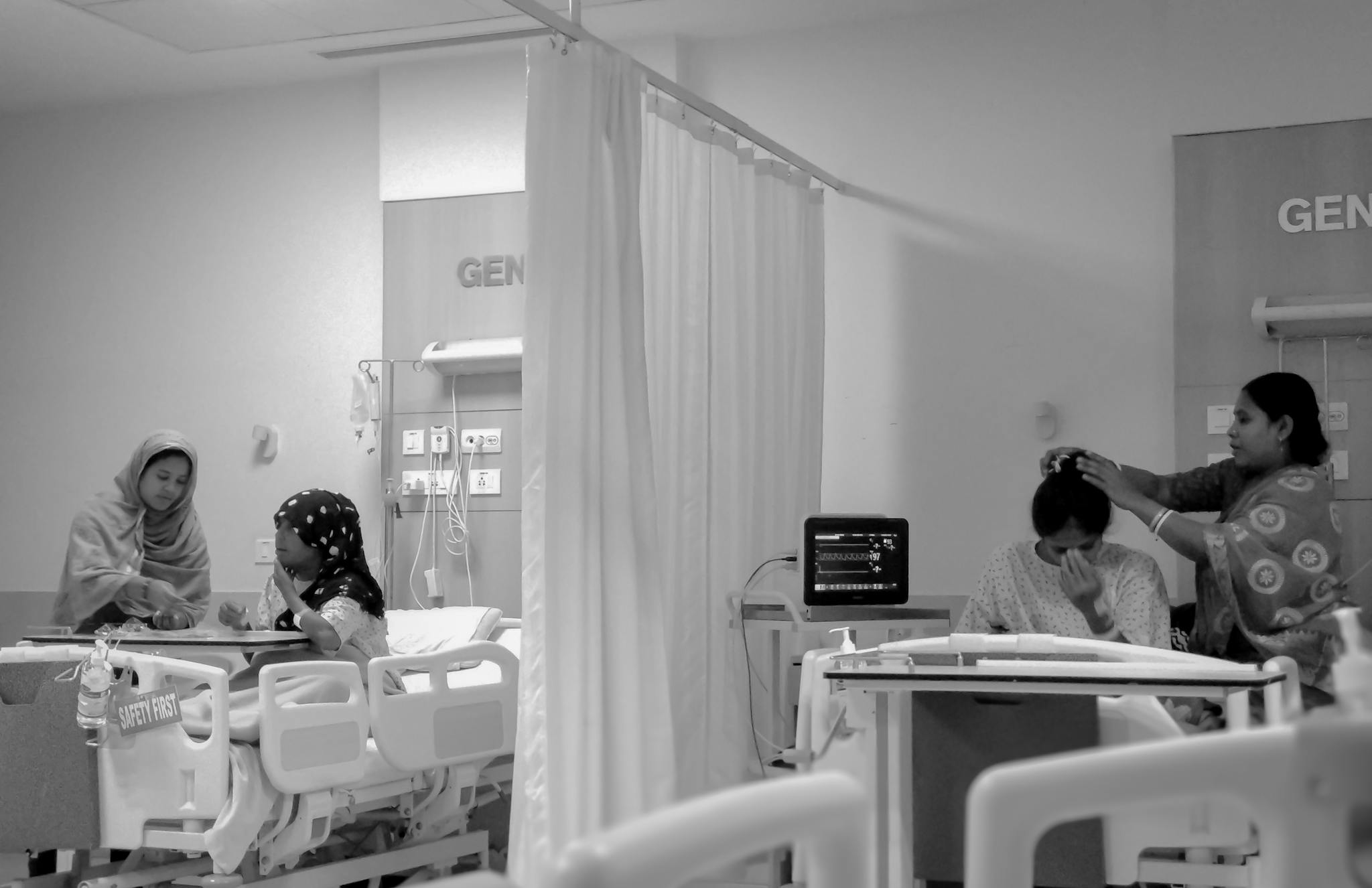 Women caring for patients in a Kolkata hospital room, focusing on recovery.